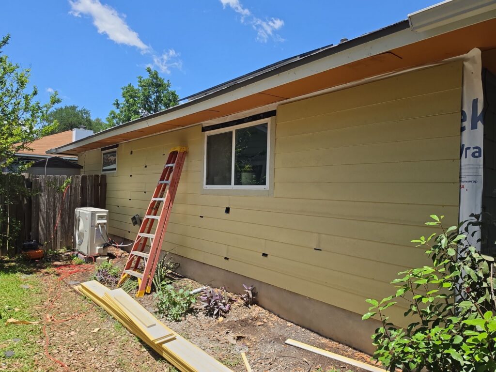 Full elevation of a Central Texas home mid siding replacement by Driftwood Builders Roofing, with new fibre cement boards installed over a new weather barrier