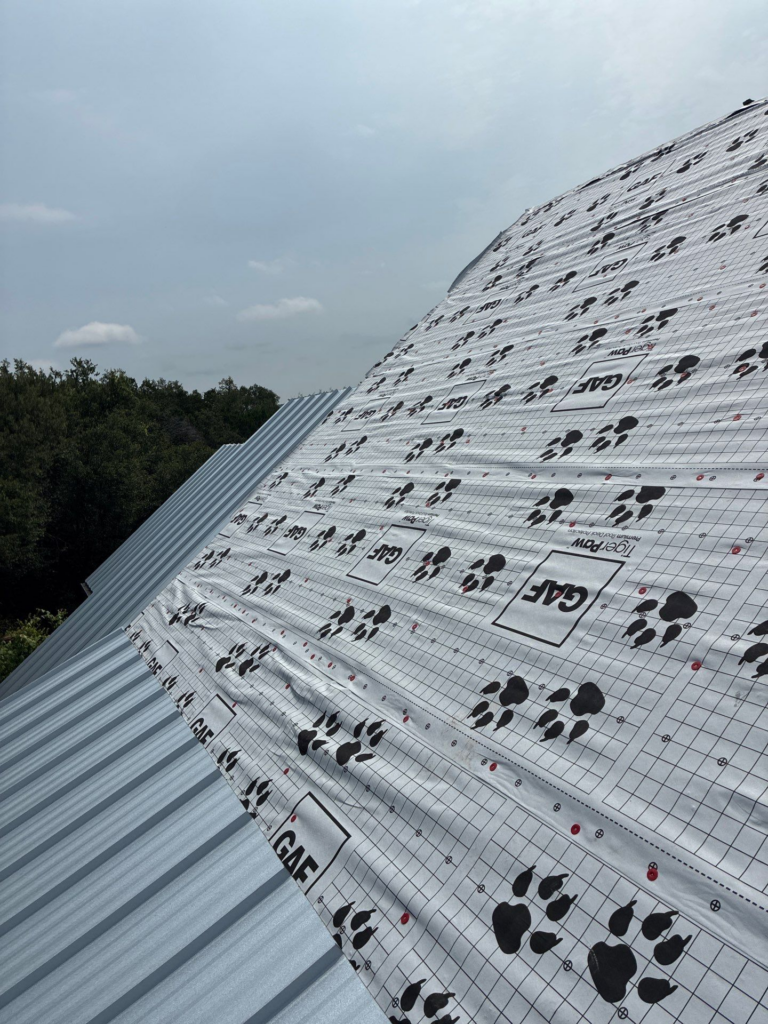 Wimberley_During_2 - Driftwood Builders Roofing Pitched metal roof with silver panels and GAF-branded waterproofing underlayment showing grid pattern and red fasteners