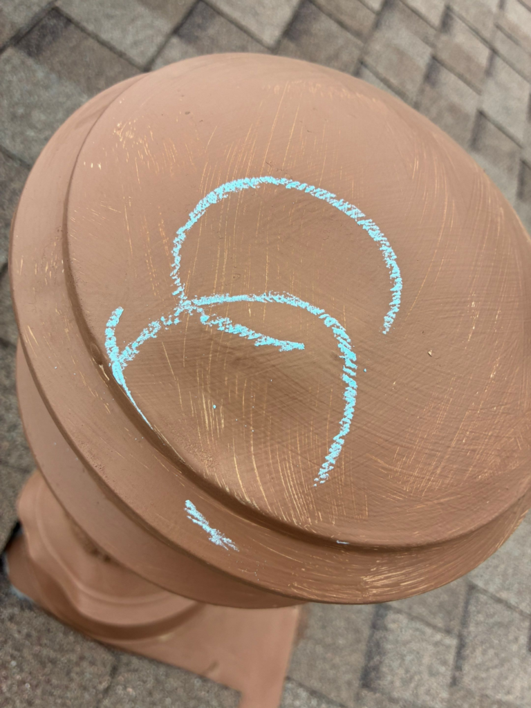 Close-up of stacked terracotta pots with blue chalk scribble forming a circular shape on the top lid.