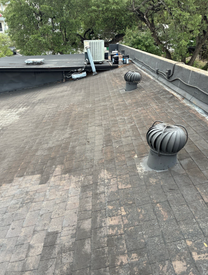 Rooftop with HVAC equipment and ductwork, two round vent hoods, and a central condenser near trees in the background. - Driftwood Builders Roofing Rooftop with HVAC equipment and ductwork, two round vent hoods, and a central condenser near trees in the background.