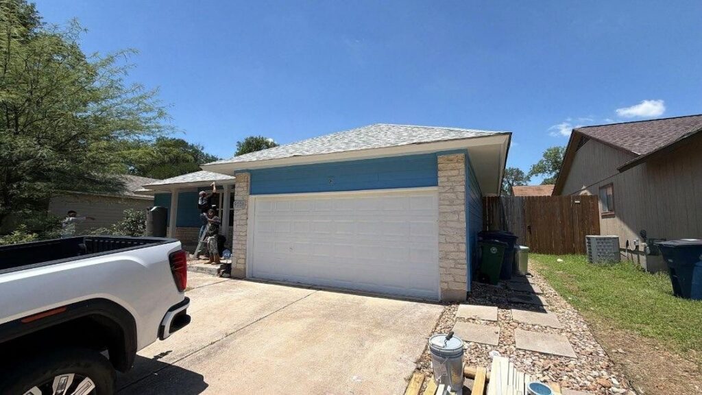 Single-story Austin home with blue siding and limestone accents during an exterior project, with a work truck in the driveway.