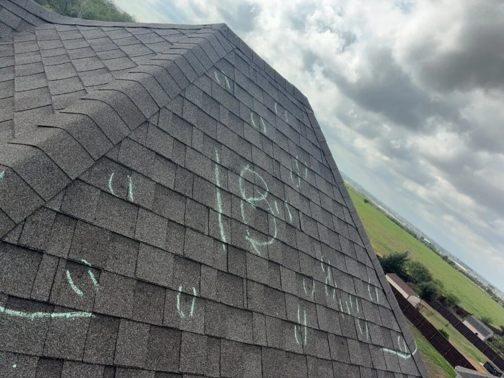 Chalk-circled hail impacts counted across an asphalt shingle slope during a Converse, TX roof inspection