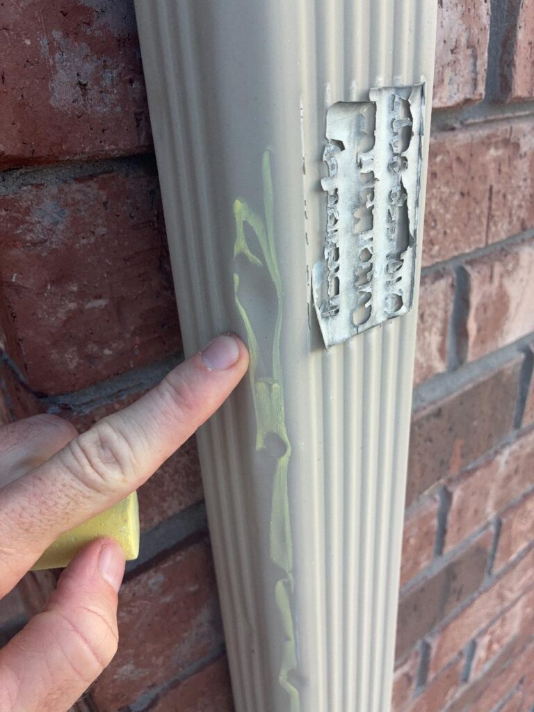 Roofer using chalk to reveal a hail dent in an aluminum downspout during a Converse, TX inspection