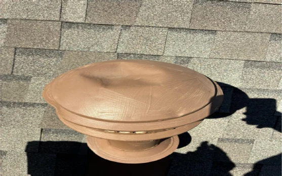 Dented metal roof exhaust vent cap from a hail impact
