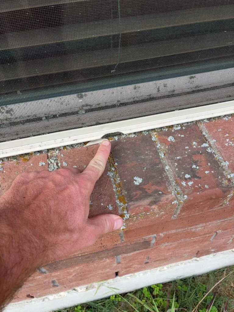 Damaged window sill track where it meets a brick rowlock sill