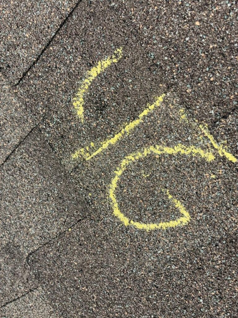 Hail impact circled in yellow chalk with a tally mark recorded beside it