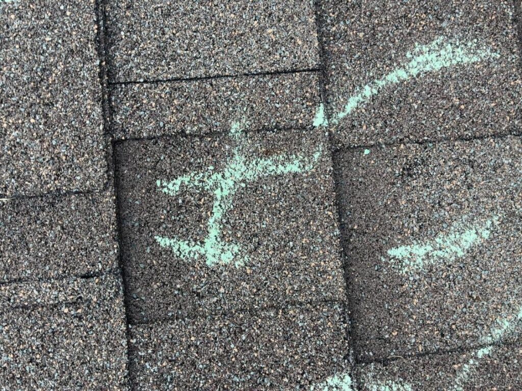 Chalk tally marks beside hail impacts across asphalt shingles on a Schertz, TX roof