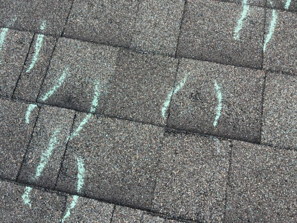 Multiple hail impacts individually marked in chalk across one asphalt shingle slope