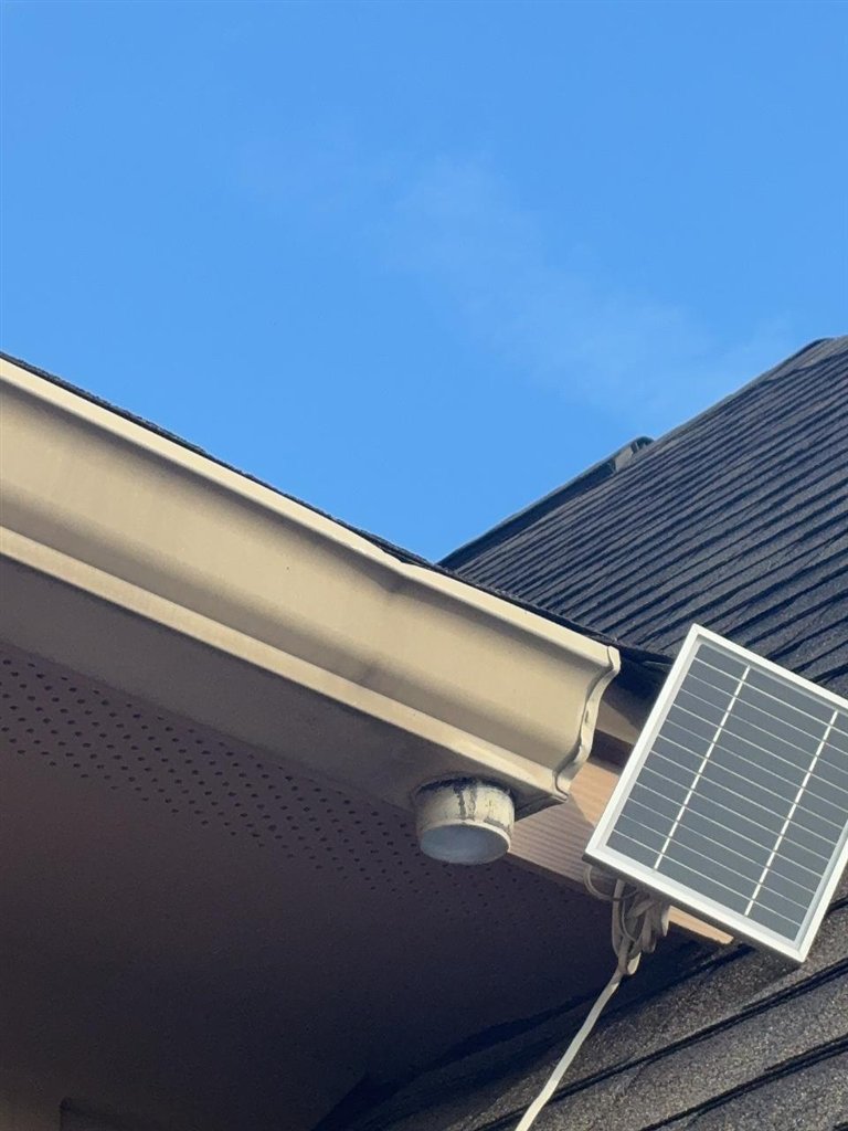 Gutter and soffit on a Schertz, Texas home photographed from below, showing a crease in the gutter face near the downspout outlet