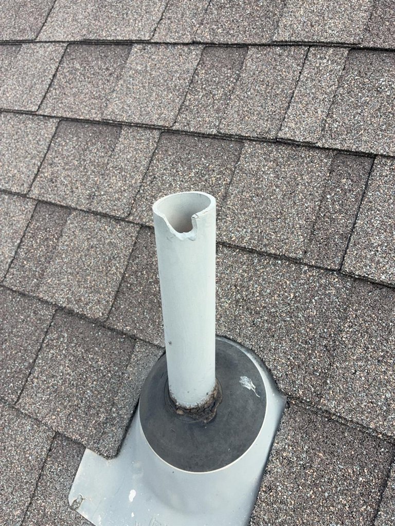 PVC plumbing vent on a Schertz, Texas roof with a piece broken out of the rim and cracked sealant at the base of the pipe boot