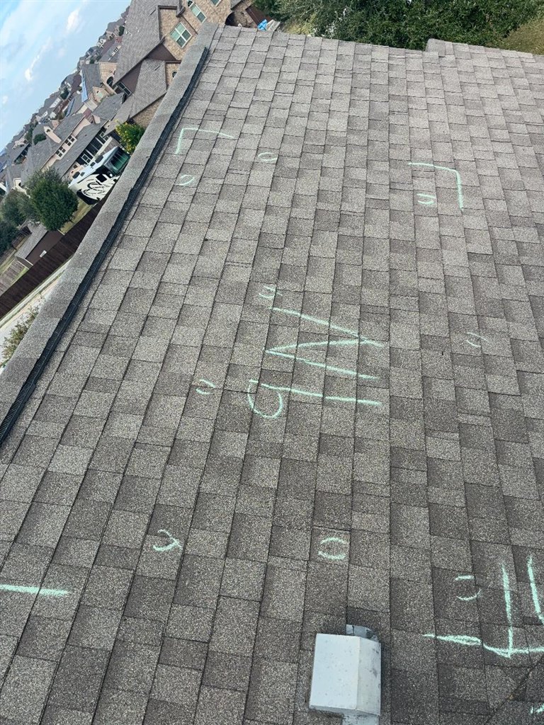 Asphalt shingle roof slope in Schertz, Texas with individual hail impacts circled in chalk and a slope marker written across the field