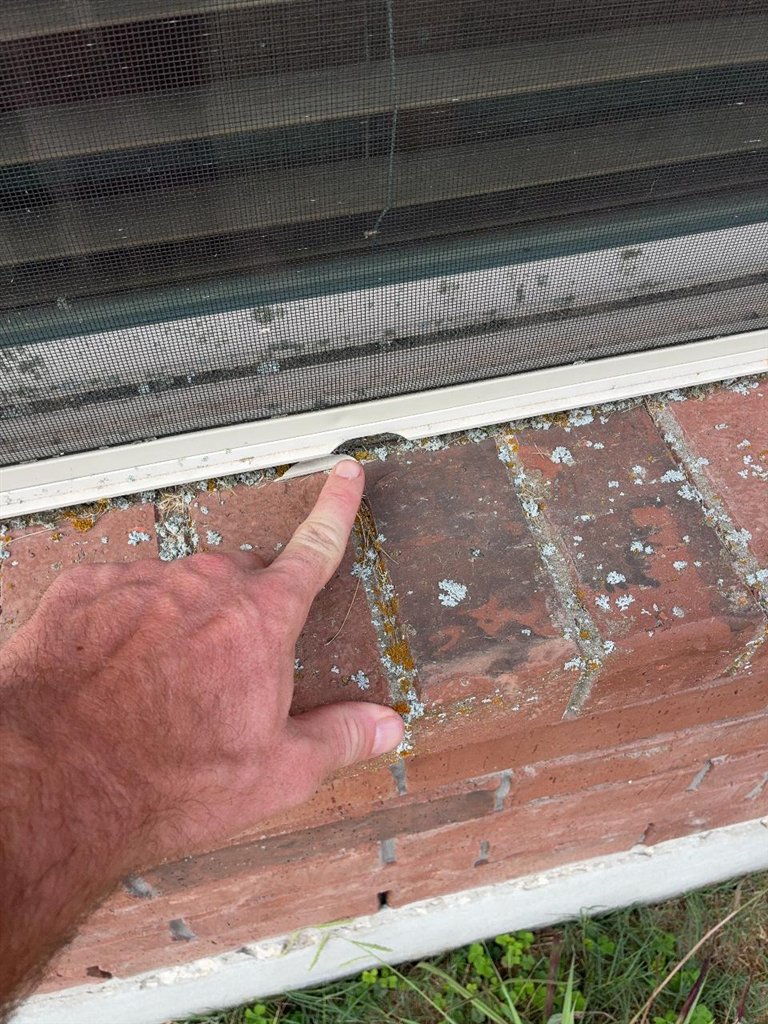 Inspector indicating a dent in the painted aluminium sill below a window screen on a Schertz, Texas home