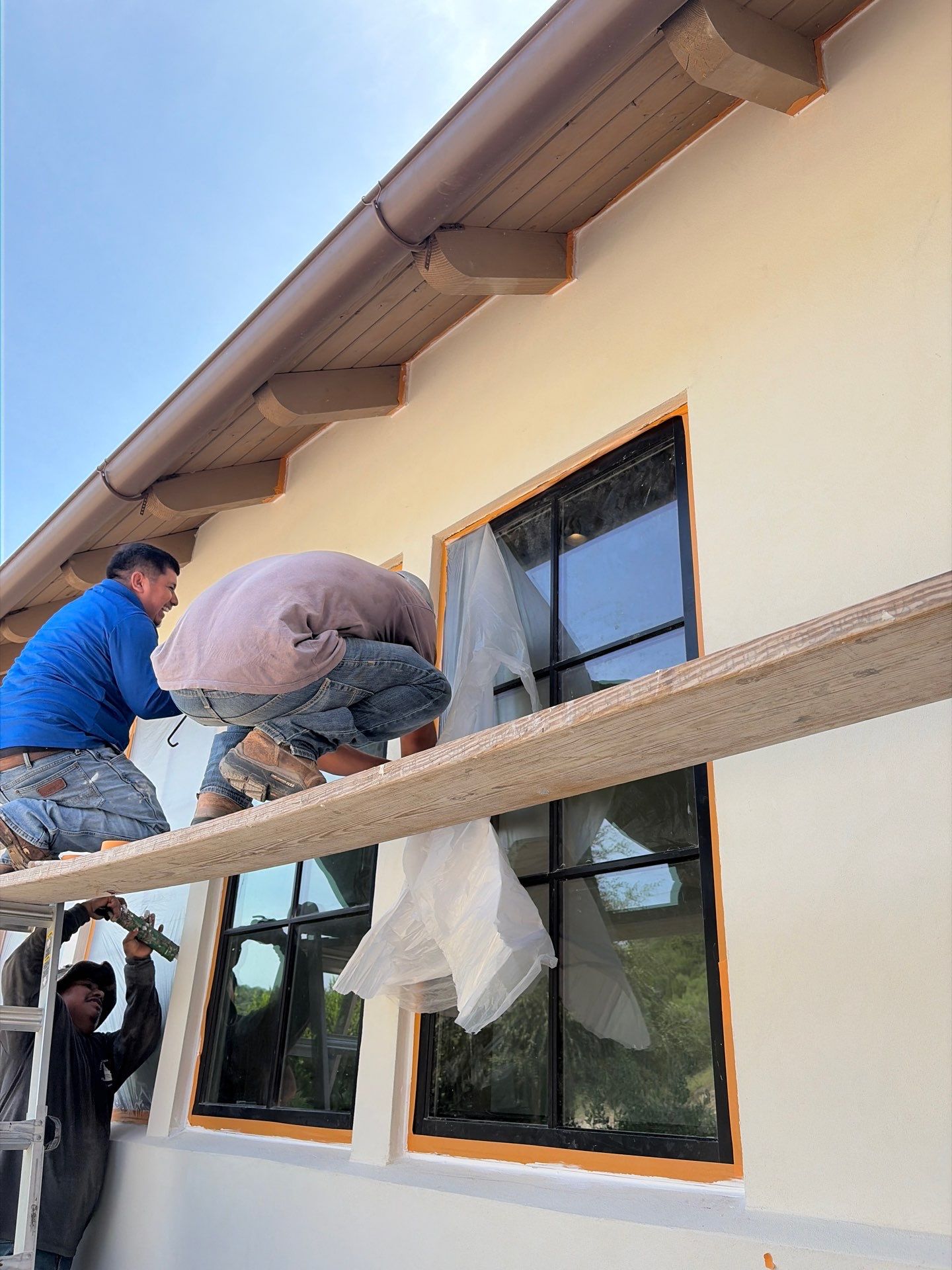 Driftwood Builders Roofing crew masking windows and trim to prepare James Hardie siding for painting on a Westlake, Austin project