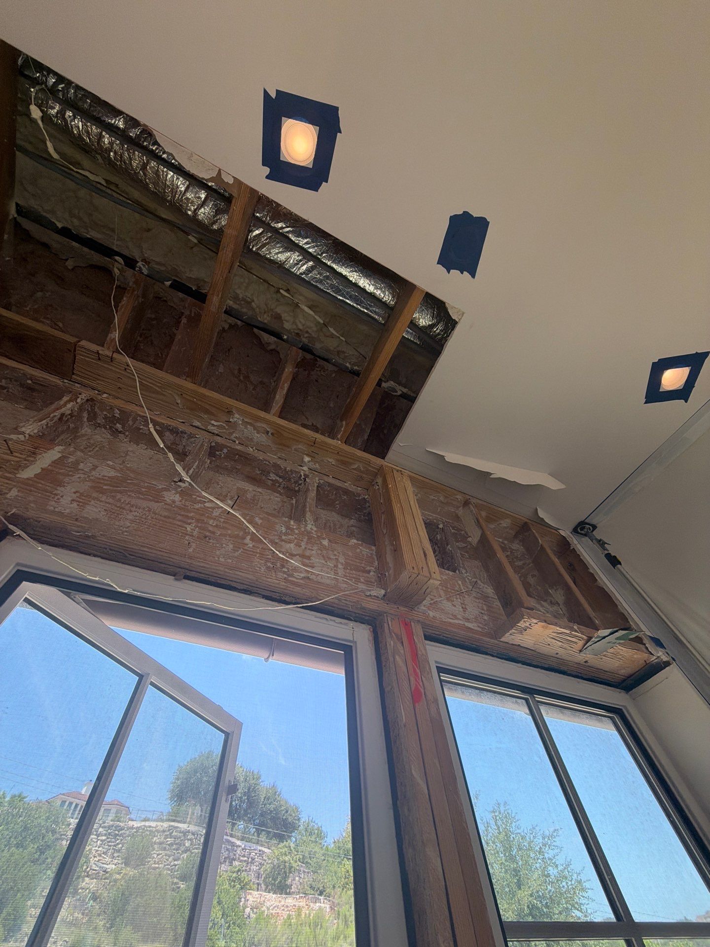 Exposed and stained wall framing above windows during the Westlake, Austin stucco restoration project where termite damage was discovered behind the original stucco