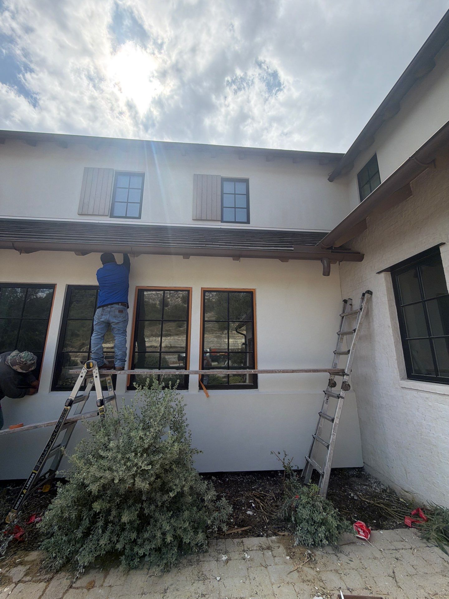 Driftwood Builders Roofing crew installing new primed window trim during a Westlake, Austin siding and stucco restoration project