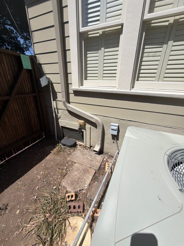 A downspout emptying right beside the foundation of an Austin home instead of draining away