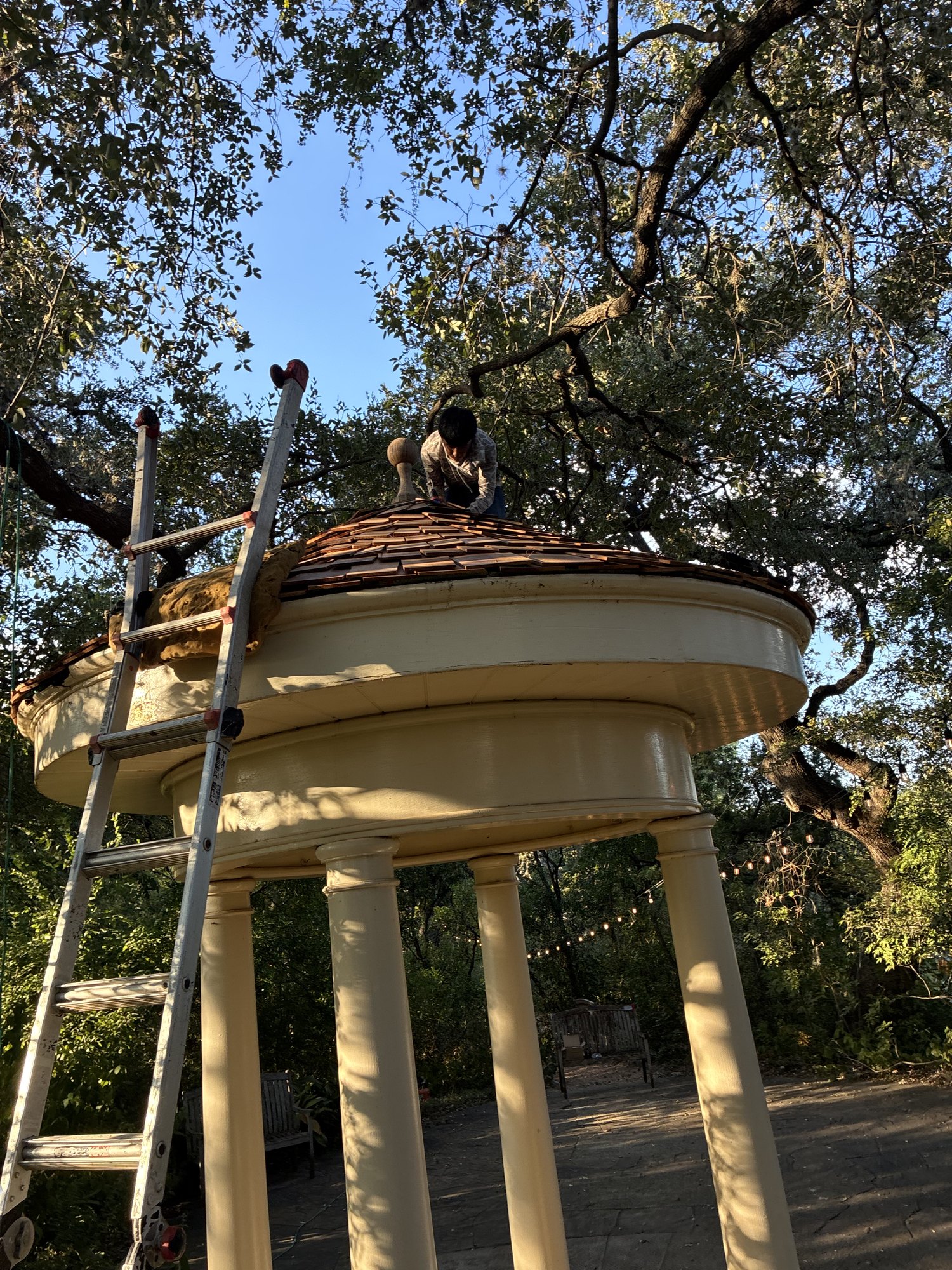 Gazebo at The Contemporary Austin Laguna Gloria with its new cedar roof, a roofer working near the finial